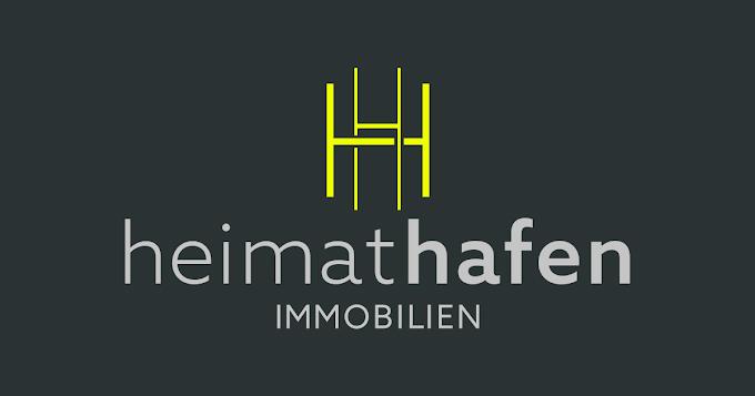 Logo von "heimathafen Immobilien" mit schriftlichem und grafischem Element in Gelb und Grau auf dunklem Hintergrund.