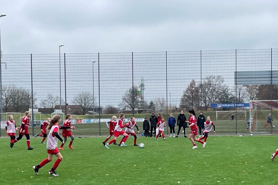 Mannschaftssport auf einem Fußballplatz mit mehreren Spielerinnen in roten Trikots, die um den Ball kämpfen.