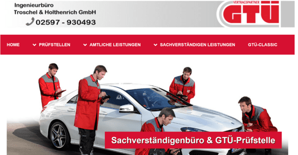 Vier Techniker in roten Overalls inspizieren ein Pkw auf einem Pr&uuml;fstand der GT&Uuml;.