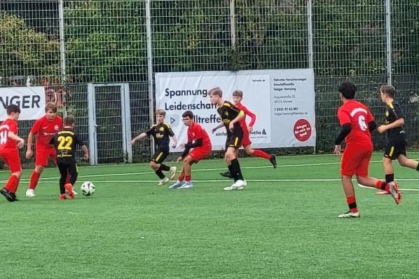 Zwei Jugendfu&szlig;ballmannschaften spielen auf einem Kunstrasenplatz, w&auml;hrend ein Spieler mit der Nummer 22 den Ball f&uuml;hrt.