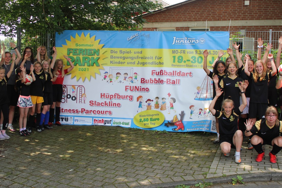 Gruppierung von Jugendlichen in Sportkleidung vor einem Werbebanner f&uuml;r eine Freizeitveranstaltung im Freien.