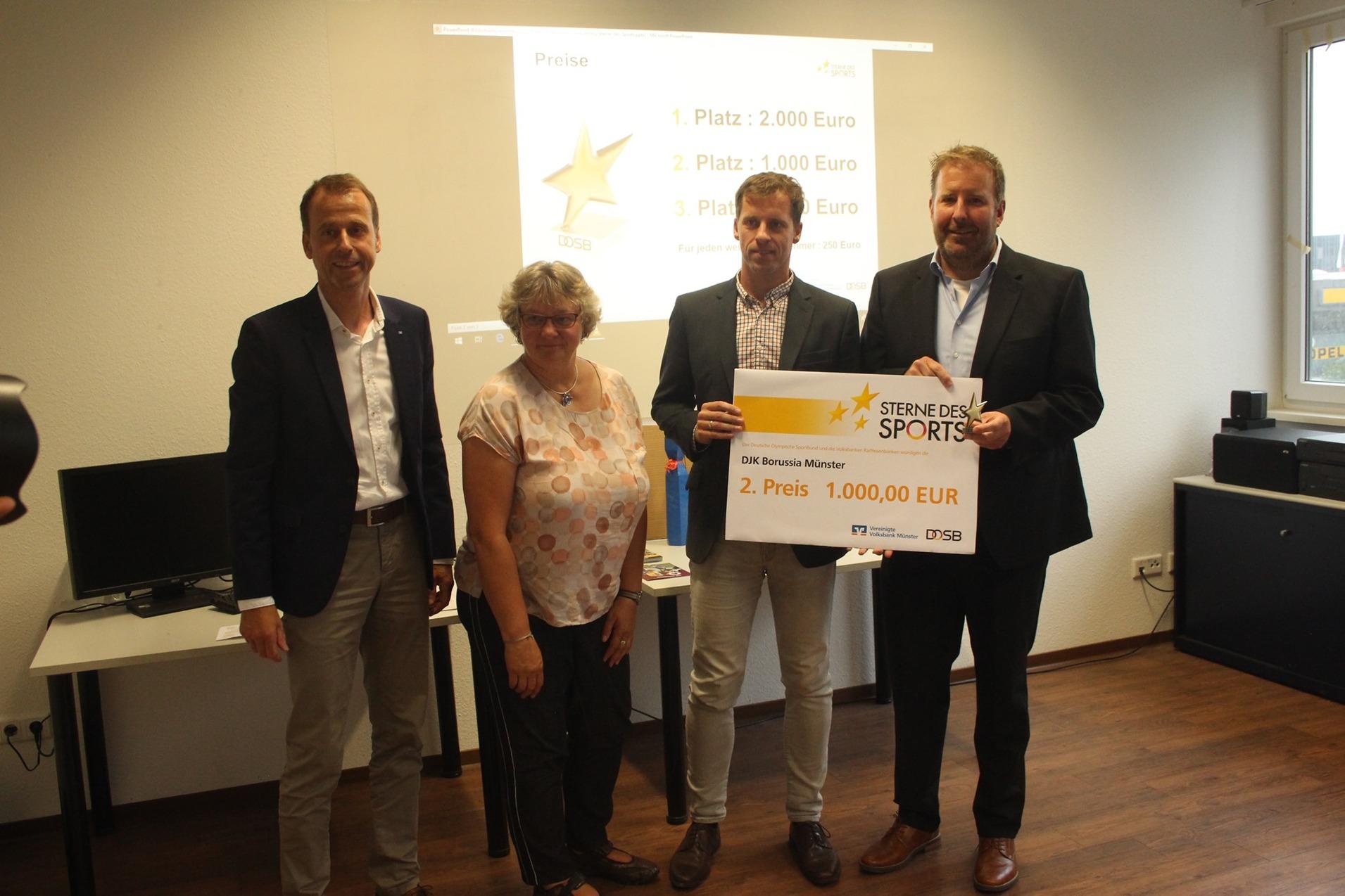 Vier Personen stehen in einem Raum und halten ein gro&szlig;es Preis-Zertifikat f&uuml;r den zweiten Platz beim Wettbewerb &bdquo;Sterne des Sports&ldquo;.