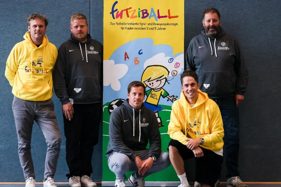 F&uuml;nf M&auml;nner in Sportswear stehen vor einem Banner mit der Aufschrift &bdquo;FurtziBALL&ldquo; und einem Kindermotiv.