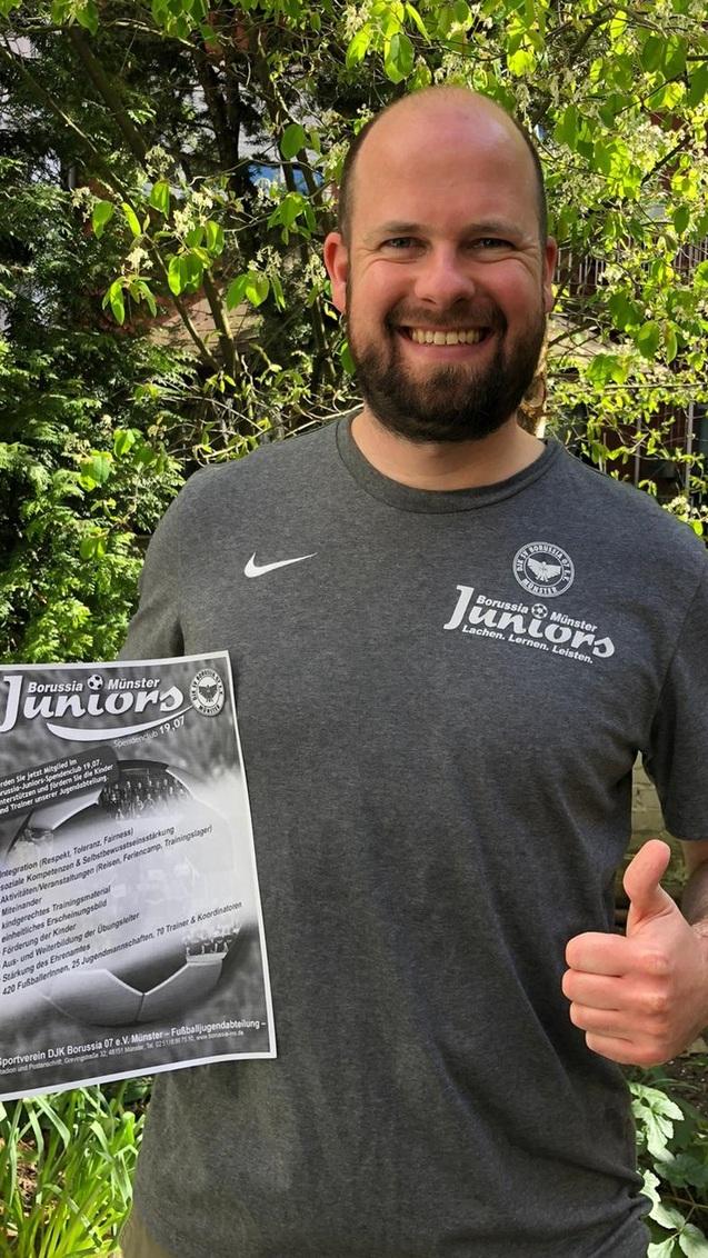 L&auml;chelnder Mann in sportlichem T-Shirt, h&auml;lt ein Informationsblatt &uuml;ber Tischtennis-Junioren im Gr&uuml;nen.