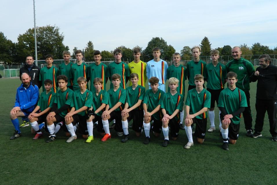 Gruppenbild einer Fu&szlig;ballmannschaft mit 22 Spielern und Trainern, gekleidet in gr&uuml;ne Trikots, auf einem Rasenplatz.