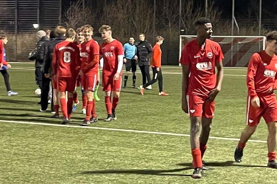 Fu&szlig;ballmannschaft in roten Trikots verl&auml;sst das Spielfeld nach einem Spiel unter Flutlicht.
