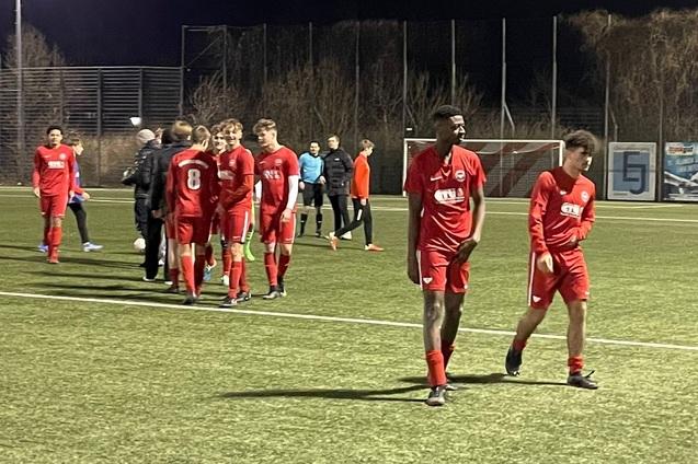Fu&szlig;ballmannschaft in roten Trikots verl&auml;sst das Spielfeld nach einem Spiel unter Flutlicht.