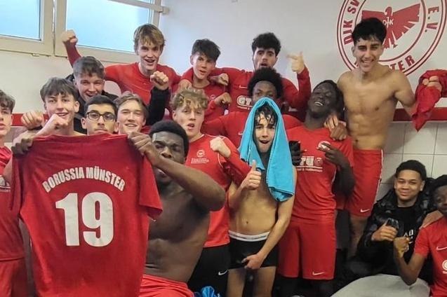 Gruppe von jubelnden jungen Fu&szlig;ballspielern in roten Trikots, einige halten ein Trikot mit der Nummer 19.