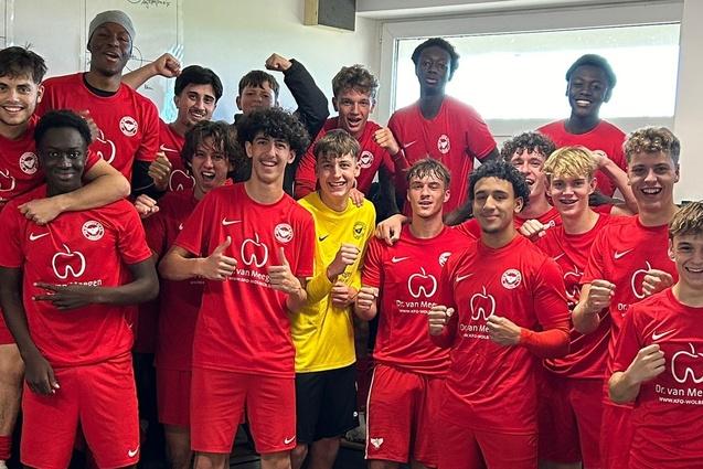 Gruppenselfie von Jugendfu&szlig;ballspielern in roten Trikots, die fr&ouml;hlich posieren und ihre Erfolge feiern.