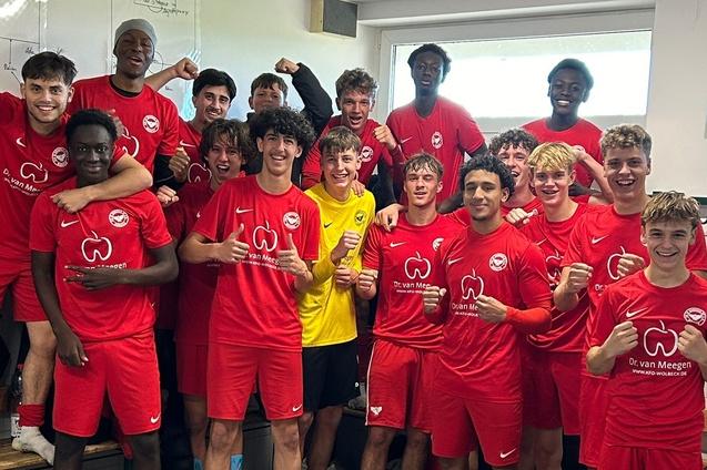 Gruppenselfie von Jugendfu&szlig;ballspielern in roten Trikots, die fr&ouml;hlich posieren und ihre Erfolge feiern.