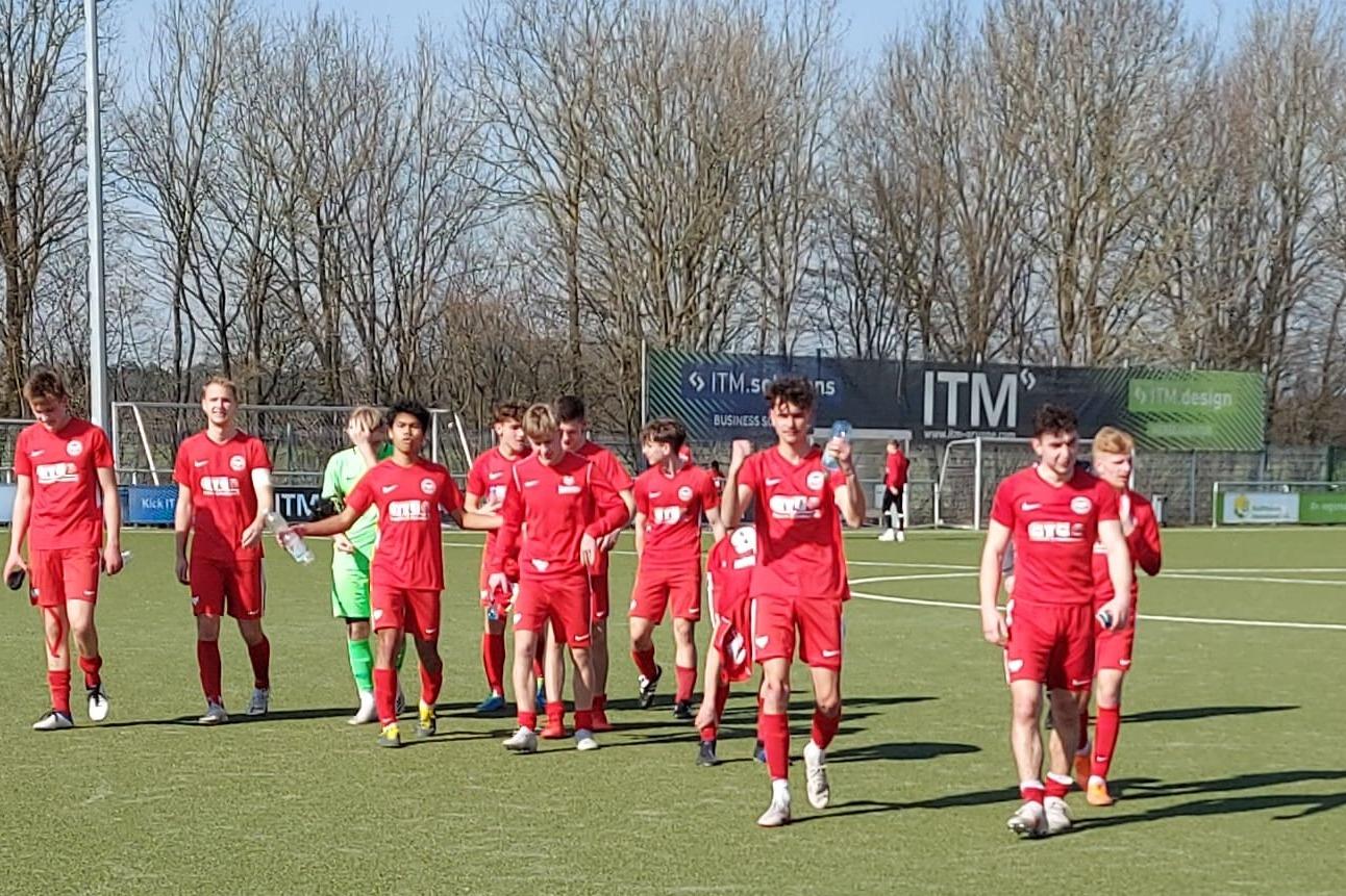 Gruppe von Spielern in roten Trikots, die auf einem Fu&szlig;ballplatz mit Kunstrasen zusammenl&auml;uft.