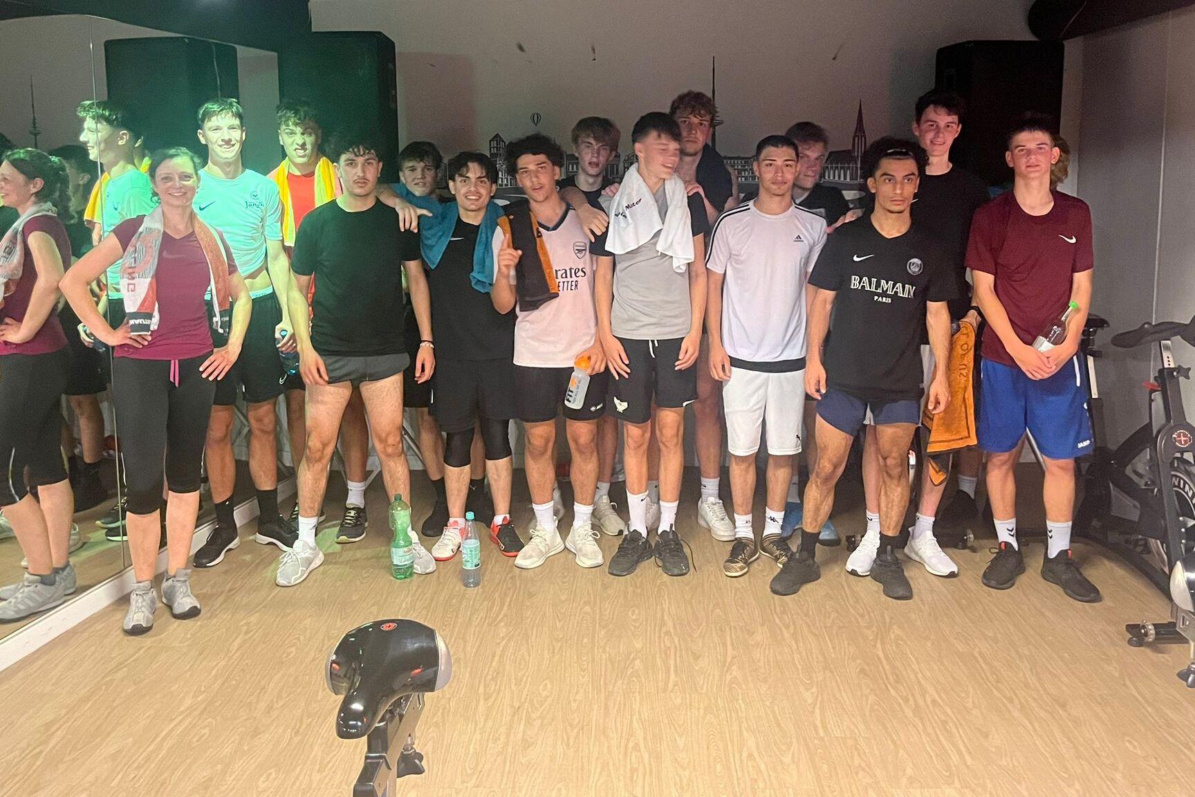 Gruppe von Jugendlichen in Sportkleidung posiert in einem Fitnessraum nach dem Training.
