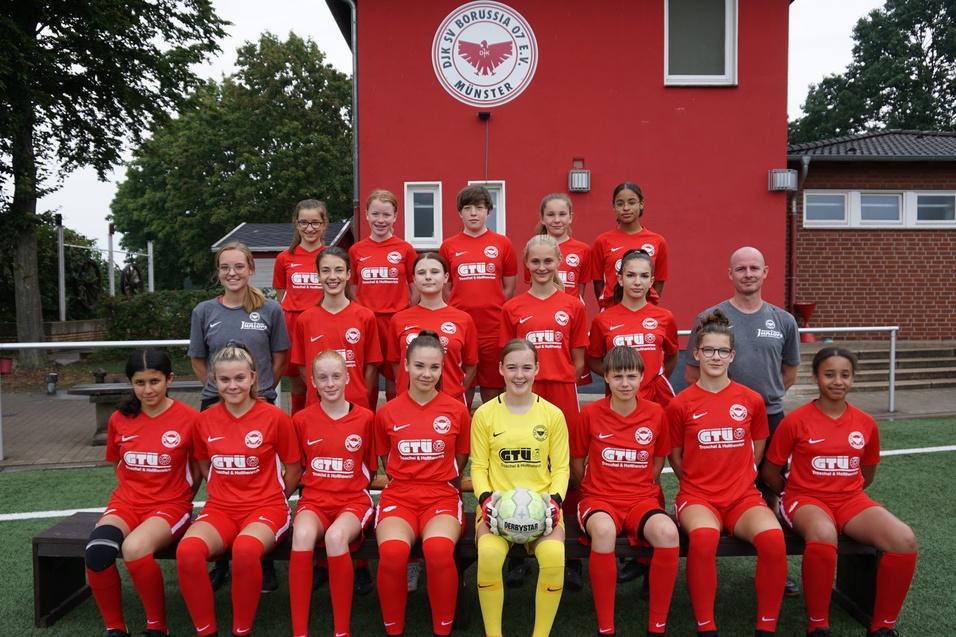 Mannschaftsfoto einer M&auml;dchenfu&szlig;ballmannschaft in roten Trikots vor einem Vereinsgeb&auml;ude.
