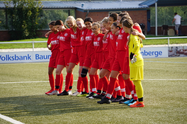 Eine Fu&szlig;ballmannschaft von M&auml;dchen in roten Trikots steht auf dem Platz, bereit f&uuml;r ein Spiel.