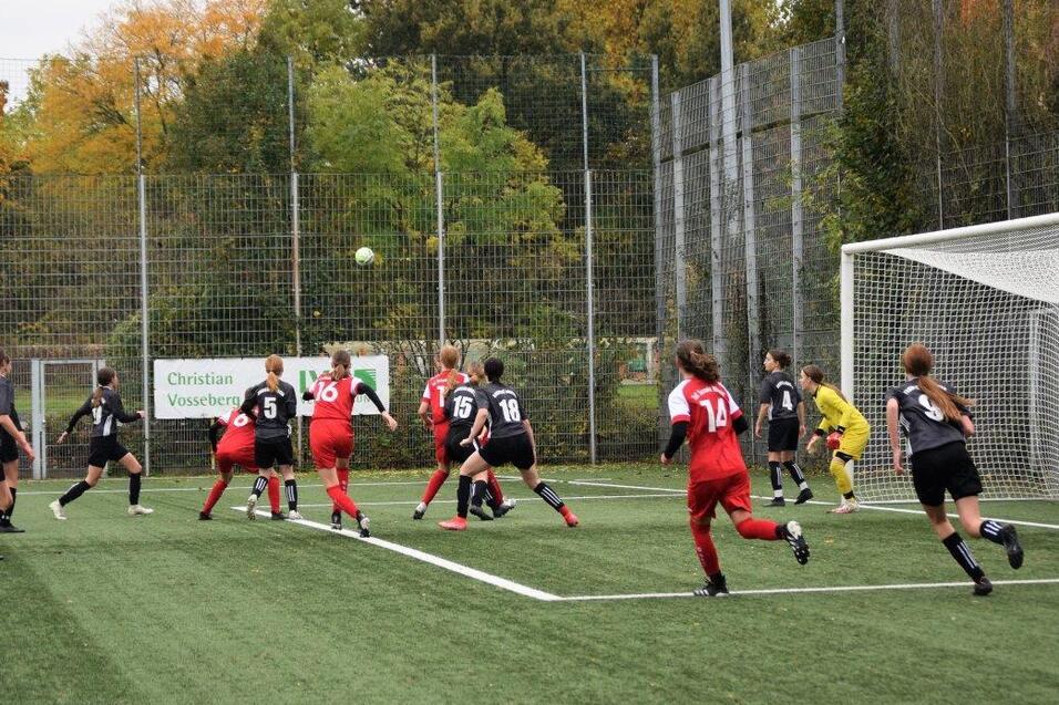 Mannschaft von M&auml;dchen beim Fu&szlig;ballspiel, mehrere Spielerinnen springen in Richtung eines hohen Balls vor dem Tor.