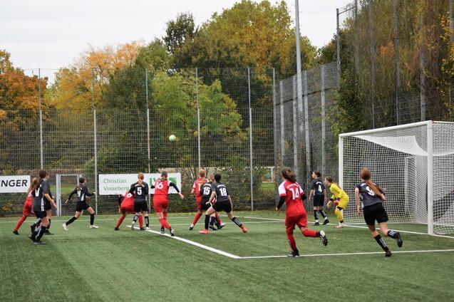 Mannschaft von M&auml;dchen beim Fu&szlig;ballspiel, mehrere Spielerinnen springen in Richtung eines hohen Balls vor dem Tor.