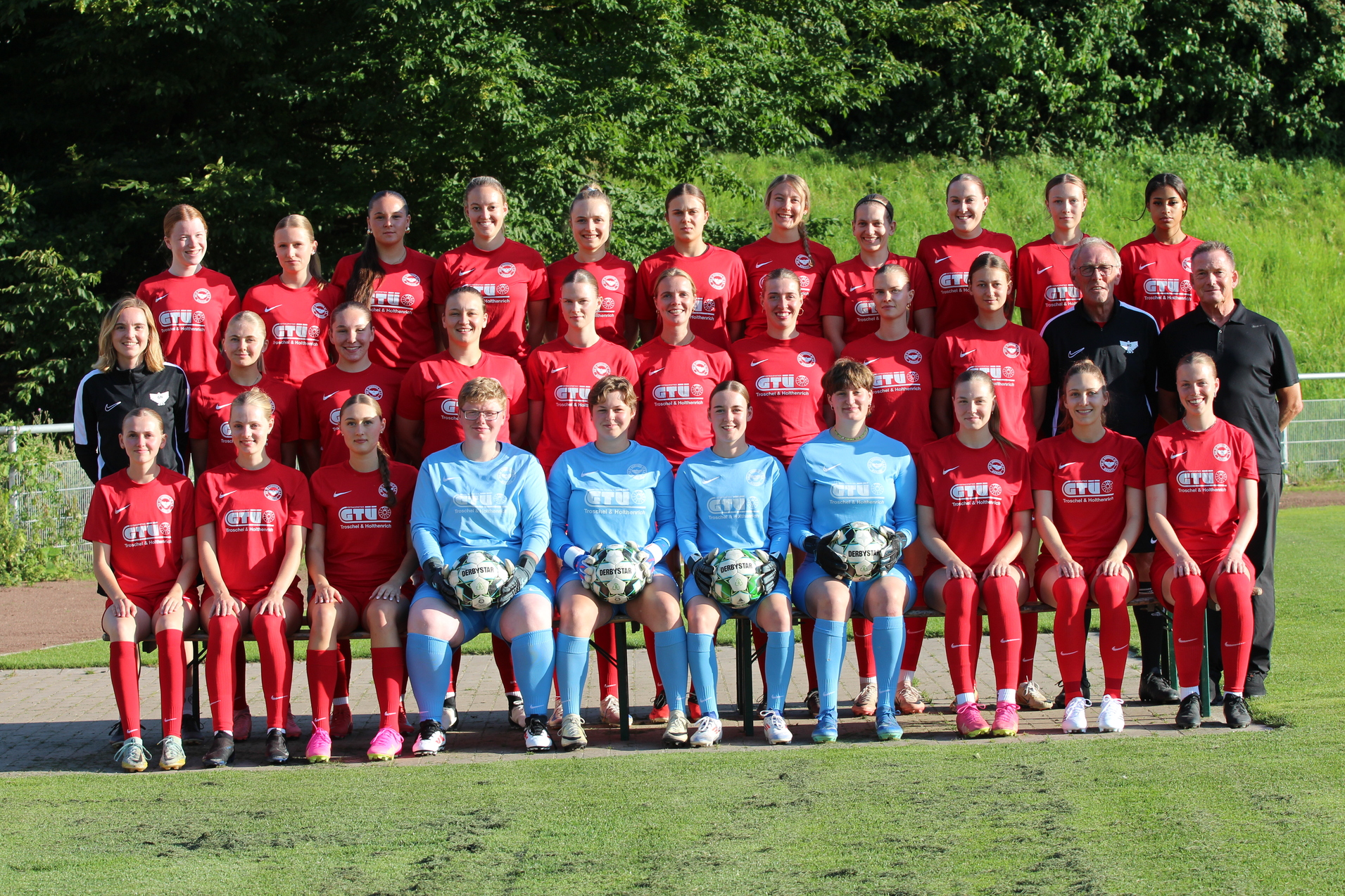 Mannschaftsfoto einer Fu&szlig;ballmannschaft mit 24 Spielerinnen in roten Trikots und zwei Torh&uuml;terinnen in blauen Trikots.