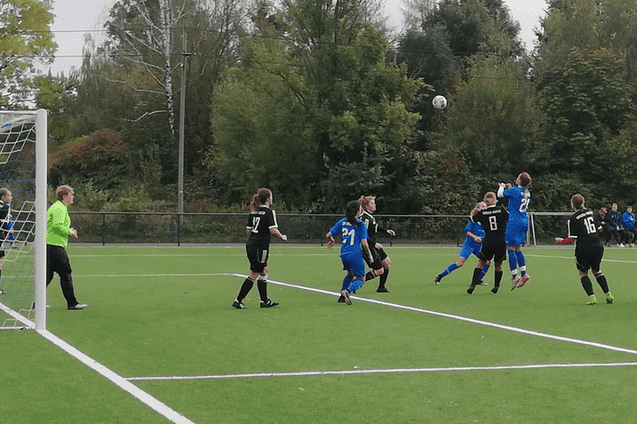 Frauenfu&szlig;ballspiel: Spielerinnen in schwarzen und blauen Trikots springen zum Kopfball auf einem Kunstrasenplatz.