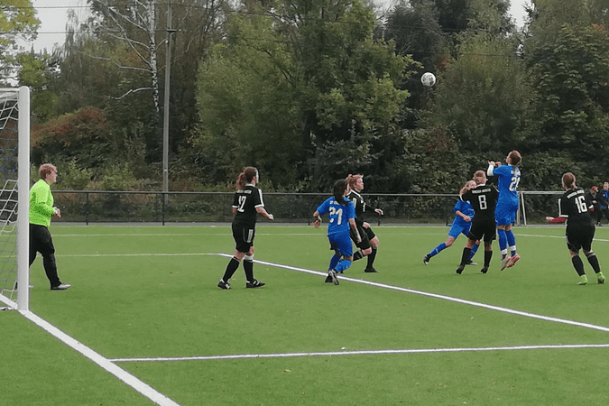 Frauenfu&szlig;ballspiel: Spielerinnen in schwarzen und blauen Trikots springen zum Kopfball auf einem Kunstrasenplatz.