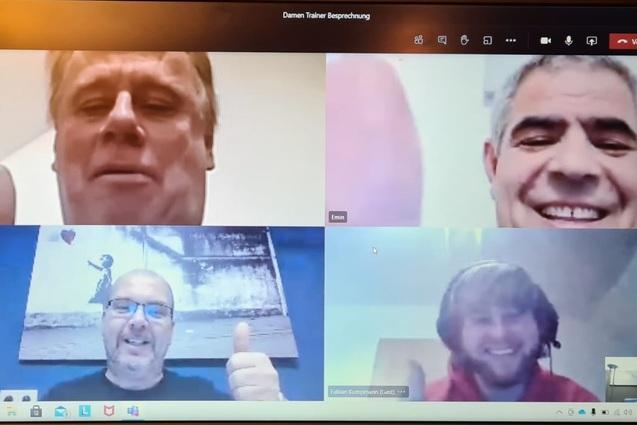 Videokonferenz mit vier M&auml;nnern, die l&auml;cheln und mit Daumen hoch zeigen, auf einem Laptop-Bildschirm.