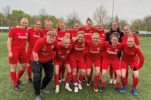 Gruppenfoto von 16 Fu&szlig;ballspielerinnen in roten Trikots auf einem Rasenplatz, smiling und in sportlicher Pose.