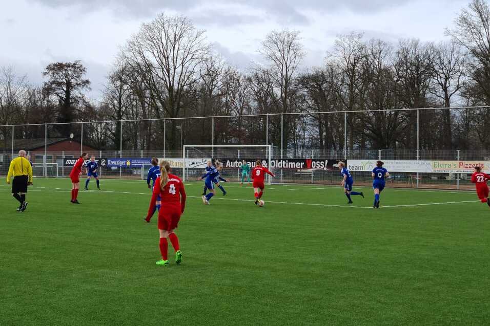 Fu&szlig;ballspiel auf einem Kunstrasenplatz mit Spielern in roten und blauen Trikots und einem Schiedsrichter.