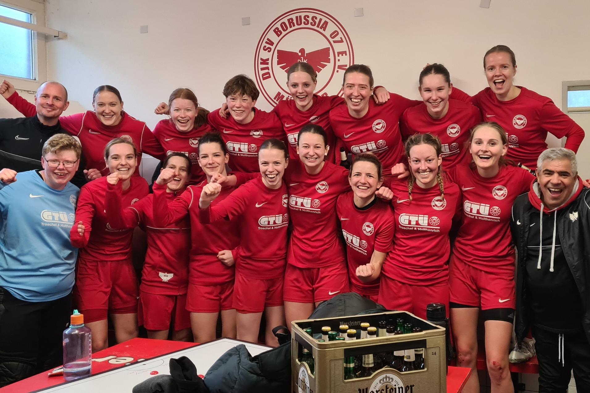 Gruppe von Frauen in roten Sporttrikots posiert freudig in der Umkleidekabine nach dem Spiel.