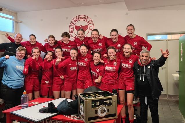 Gruppe von Frauen in roten Sporttrikots posiert freudig in der Umkleidekabine nach dem Spiel.