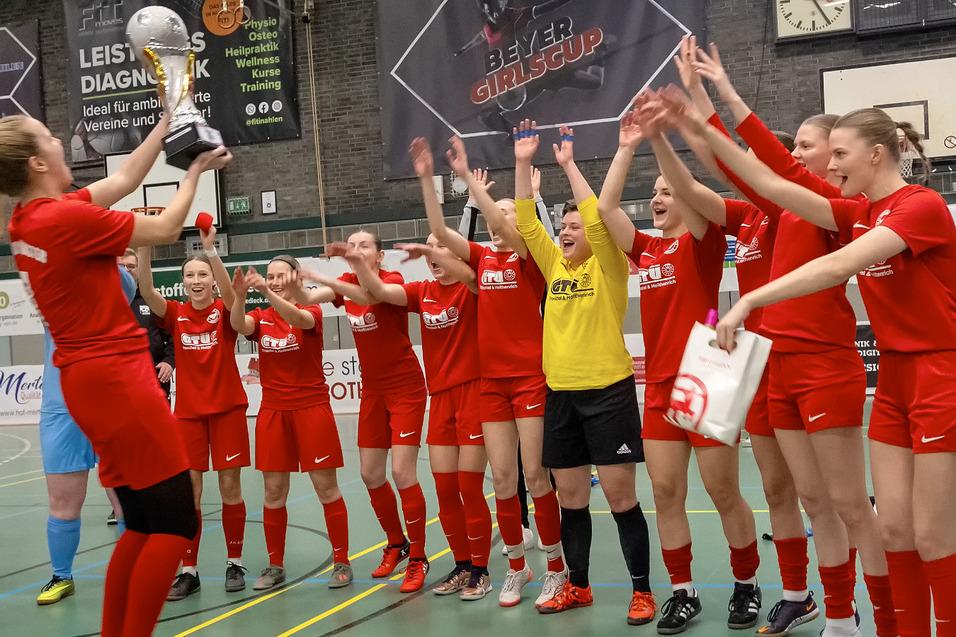 Frauenfu&szlig;ballmannschaft jubelt und feiert mit Pokal in der Sporthalle nach einem gewonnenen Turnier.