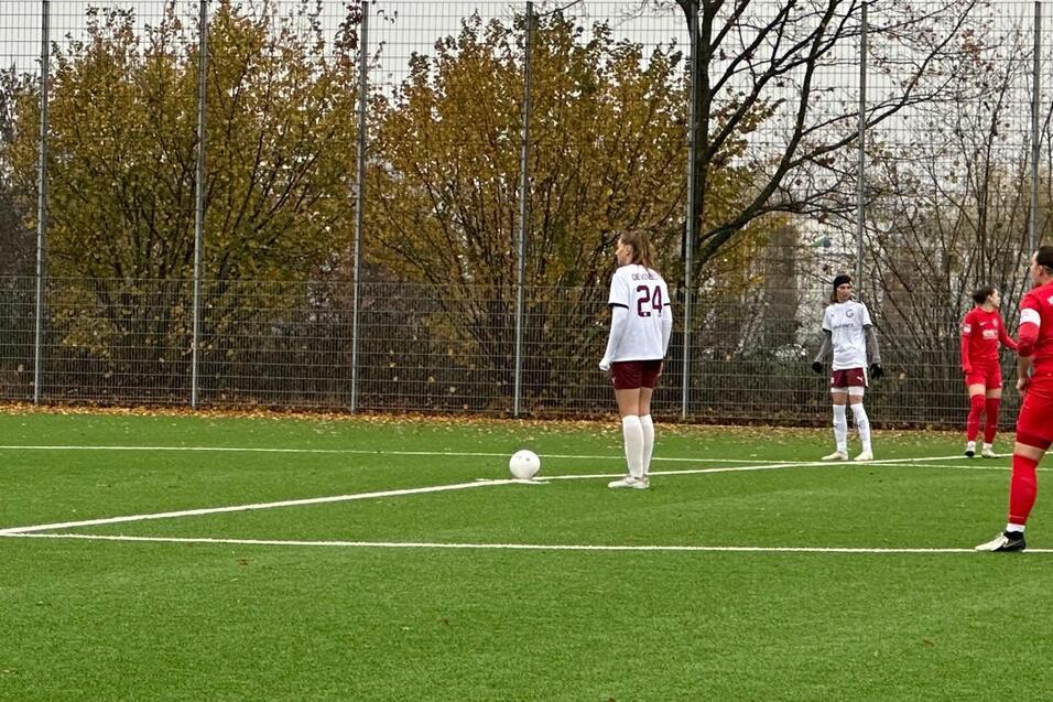 Frauenfu&szlig;ballspiel auf Kunstrasen, Spielerinnen in roten und wei&szlig;en Trikots, Ball liegt zum Ansto&szlig; bereit.