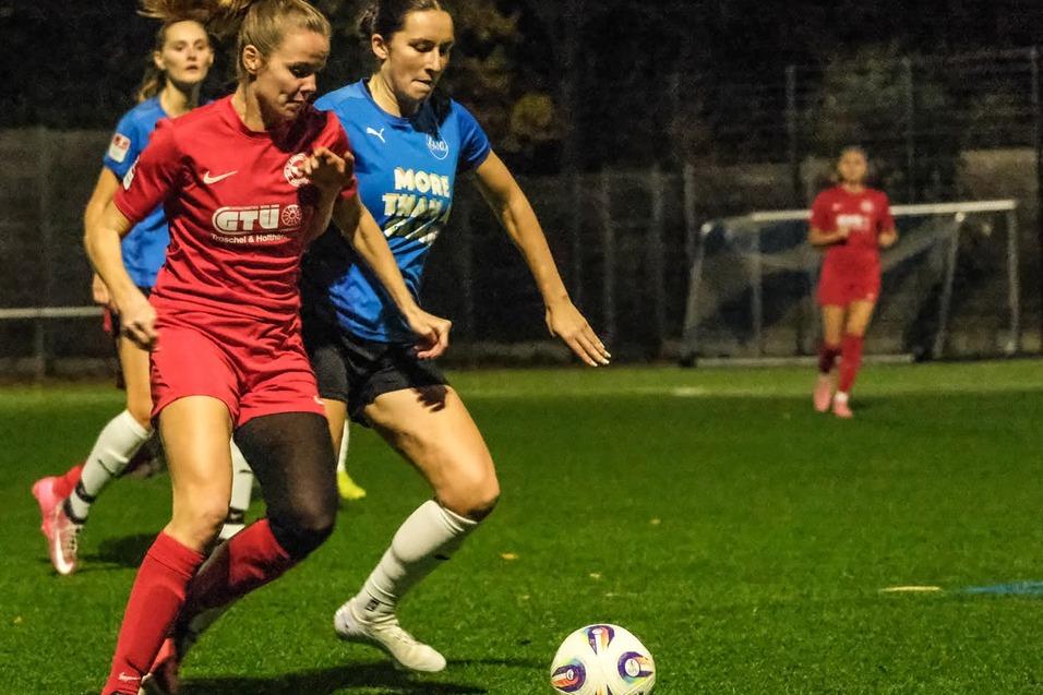 Zwei Fu&szlig;ballspielerinnen in Aktion auf einem Kunstrasenplatz, mit einem Ball zwischen ihnen.