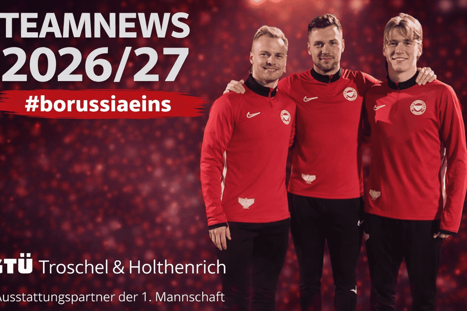 Drei Fu&szlig;ballspieler in roten Trainingsanz&uuml;gen stehen l&auml;chelnd vor einem unscharfen, leuchtenden Hintergrund.