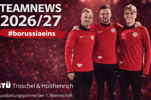 Drei Fu&szlig;ballspieler in roten Trainingsanz&uuml;gen stehen l&auml;chelnd vor einem unscharfen, leuchtenden Hintergrund.
