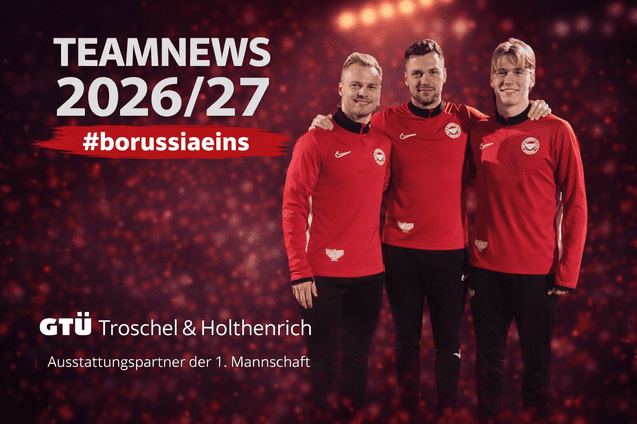 Drei Fu&szlig;ballspieler in roten Trainingsanz&uuml;gen stehen l&auml;chelnd vor einem unscharfen, leuchtenden Hintergrund.