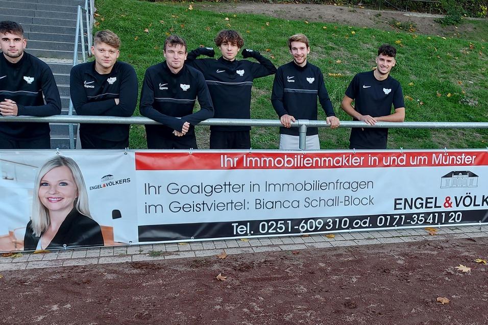 Sechs Personen in schwarzer Kleidung stehen l&auml;chelnd vor einem Banner der Immobilienagentur Engel & V&ouml;lkers.