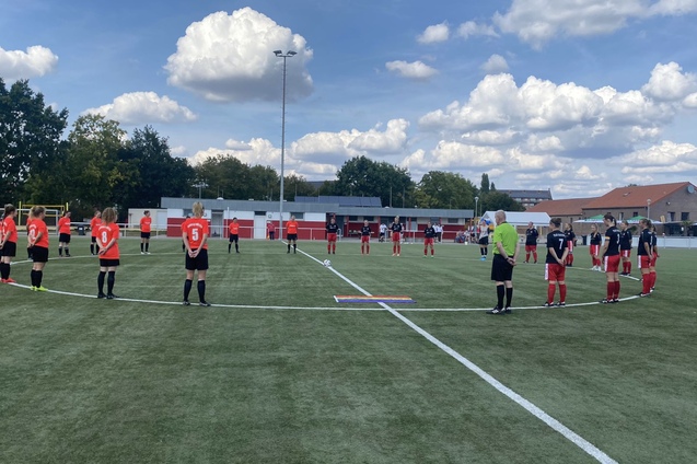 Zwei Fu&szlig;ballmannschaften stehen in einer Kreisformation auf dem Spielfeld, um einen Moment der Ehrung abzuhalten.