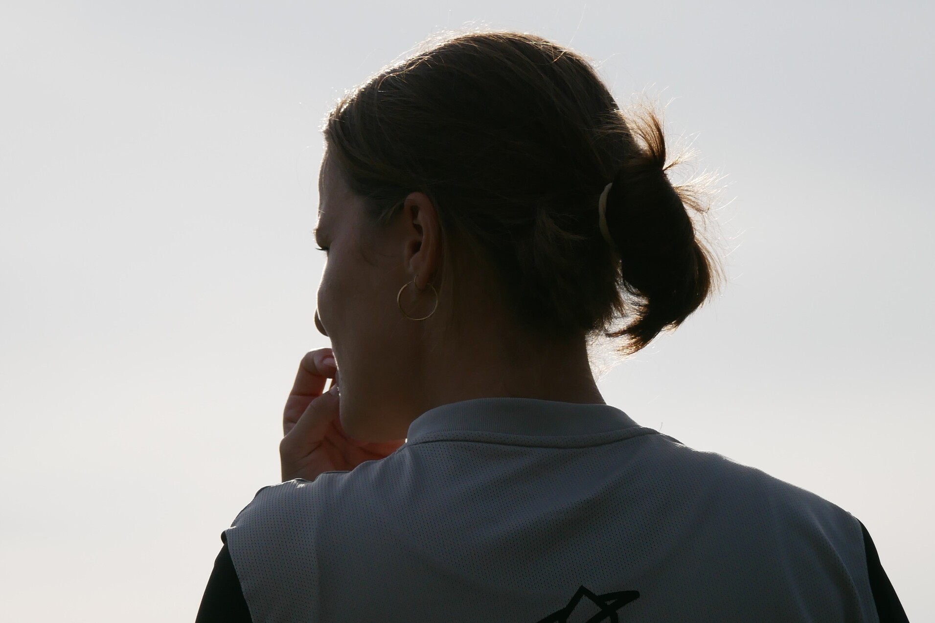 Silhouette einer Frau mit hochgestecktem Haar, die nachdenklich in eine entfernte Richtung blickt.