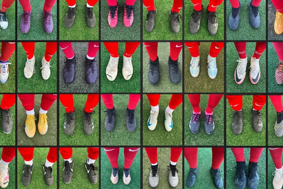 Muster einer Schuhreihe mit verschiedenen Fu&szlig;ballschuhen auf einem gr&uuml;nen Kunstrasenfeld.
