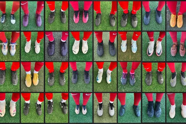 Muster einer Schuhreihe mit verschiedenen Fu&szlig;ballschuhen auf einem gr&uuml;nen Kunstrasenfeld.