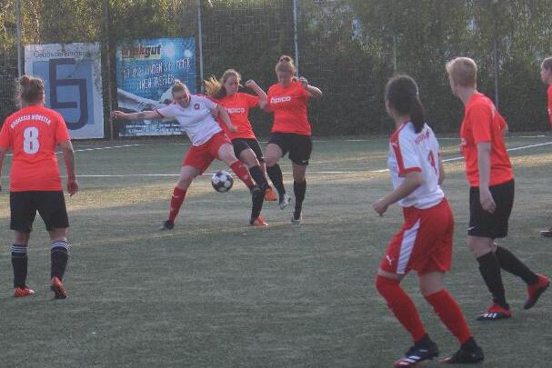 Zwei Fu&szlig;ballteams im Spiel, eine Spielerin dribbelt den Ball, w&auml;hrend andere Spielerinnen in rot und schwarz positioniert sind.
