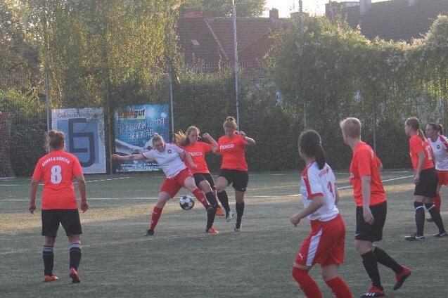 Zwei Fu&szlig;ballteams im Spiel, eine Spielerin dribbelt den Ball, w&auml;hrend andere Spielerinnen in rot und schwarz positioniert sind.