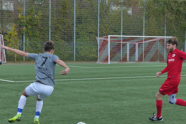 Zwei Fu&szlig;ballspieler in Aktion auf einem Kunstrasenplatz. Einer in grauem Trikot, der andere in rotem Trikot.