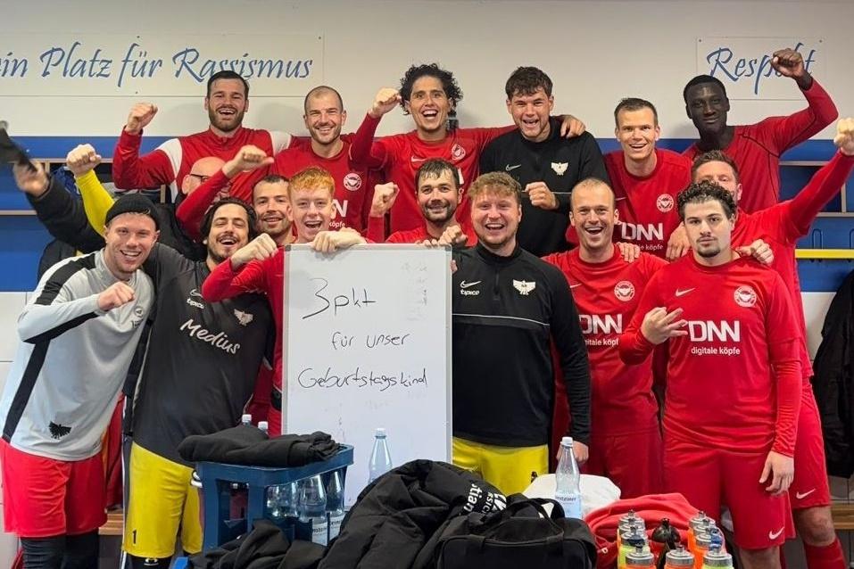 Gruppenselfie einer Fu&szlig;ballmannschaft in roten Trikots, zeigt ein Plakat mit der Aufschrift "Platz f&uuml;r unsere Gesichtswelt".