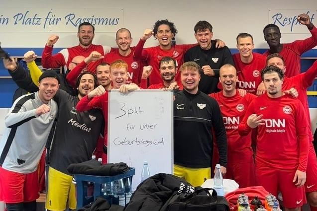 Gruppenselfie einer Fu&szlig;ballmannschaft in roten Trikots, zeigt ein Plakat mit der Aufschrift "Platz f&uuml;r unsere Gesichtswelt".