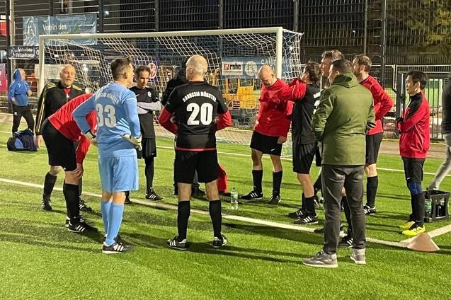 Gruppe von Fu&szlig;ballspielern und Schiedsrichtern in sportlicher Diskussion auf einem Kunstrasenplatz.
