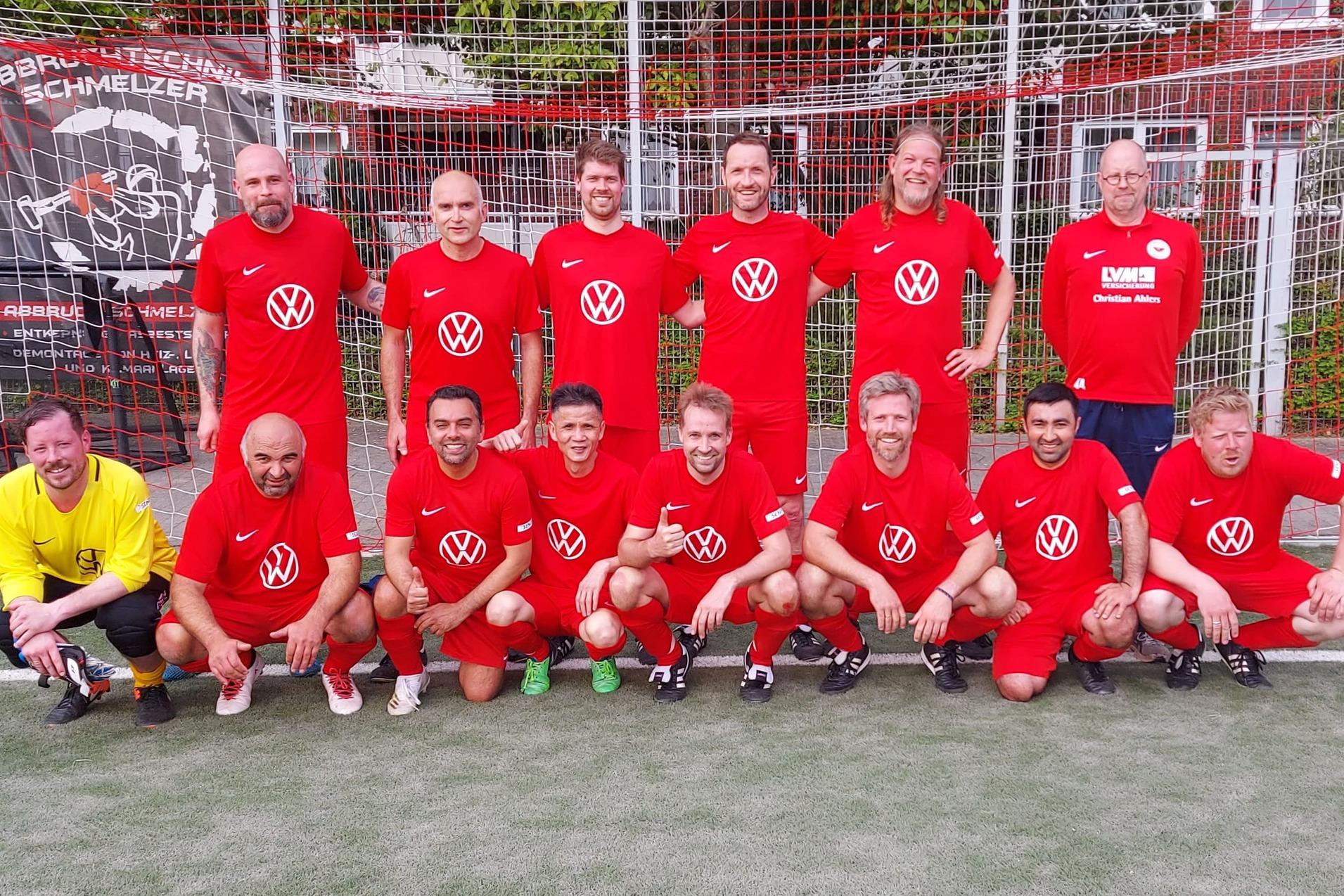 Gruppenfoto von elf Fu&szlig;ballspielern in roten Trikots vor einem Tor. Ein Torwart in Gelb sitzt vorne.