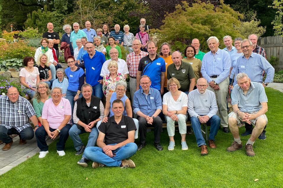 Gruppenfoto von etwa 40 Personen im Garten, umgeben von Pflanzen und B&auml;umen, l&auml;chelnd und in festlicher Stimmung.