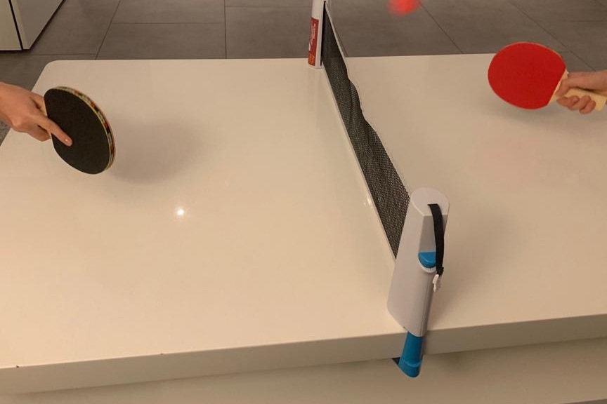 Zwei H&auml;nde mit Tischtennisschl&auml;gern spielen am Tisch, der Ball fliegt &uuml;ber das Netz.