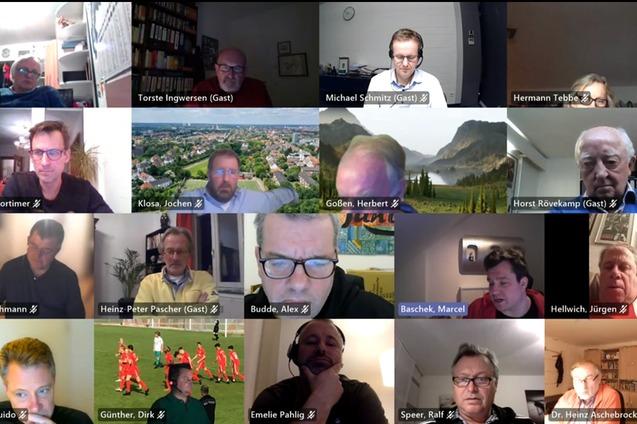 Videokonferenz mit mehreren Teilnehmern, die auf einem Raster-Hintergrund zu sehen sind, einige in kleineren Fenstern.