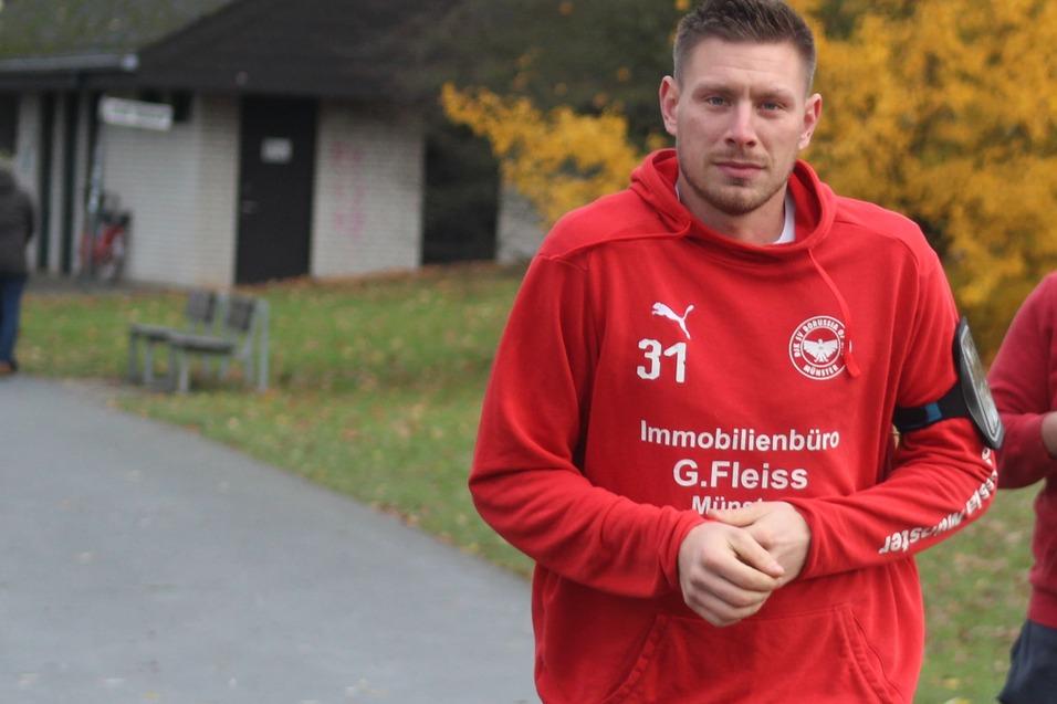 Zwei Sportler in roten Trainingsanz&uuml;gen joggen in einem Park, w&auml;hrend ein weiterer L&auml;ufer im Hintergrund vorbeil&auml;uft.